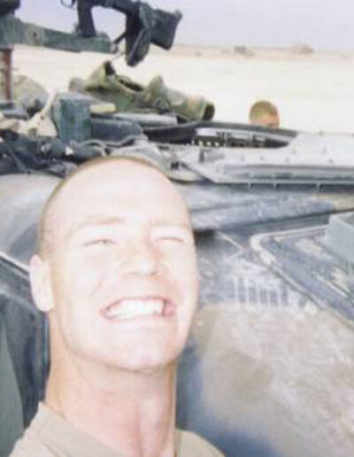 Heath writing in a notebook inside a military vehicle, surrounded by gear and supplies during his tour in Iraq.
